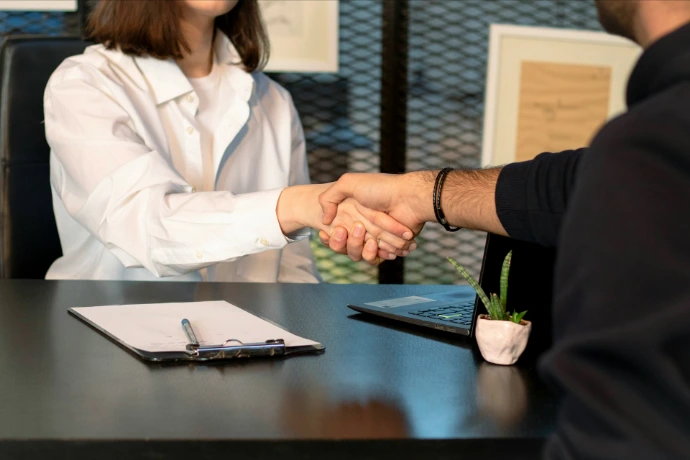 Darse las manos como simbolo de compromisi y fidelización, Alinanza, a man and a woman shaking hands in front of a laptop